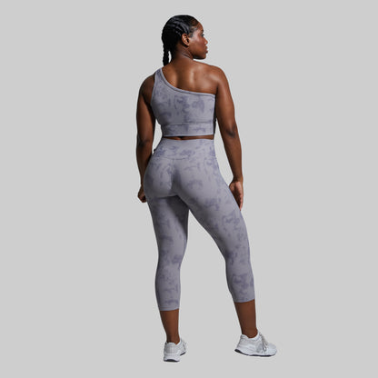 Woman wearing a gray tie-dye athletic outfit on a light gray background