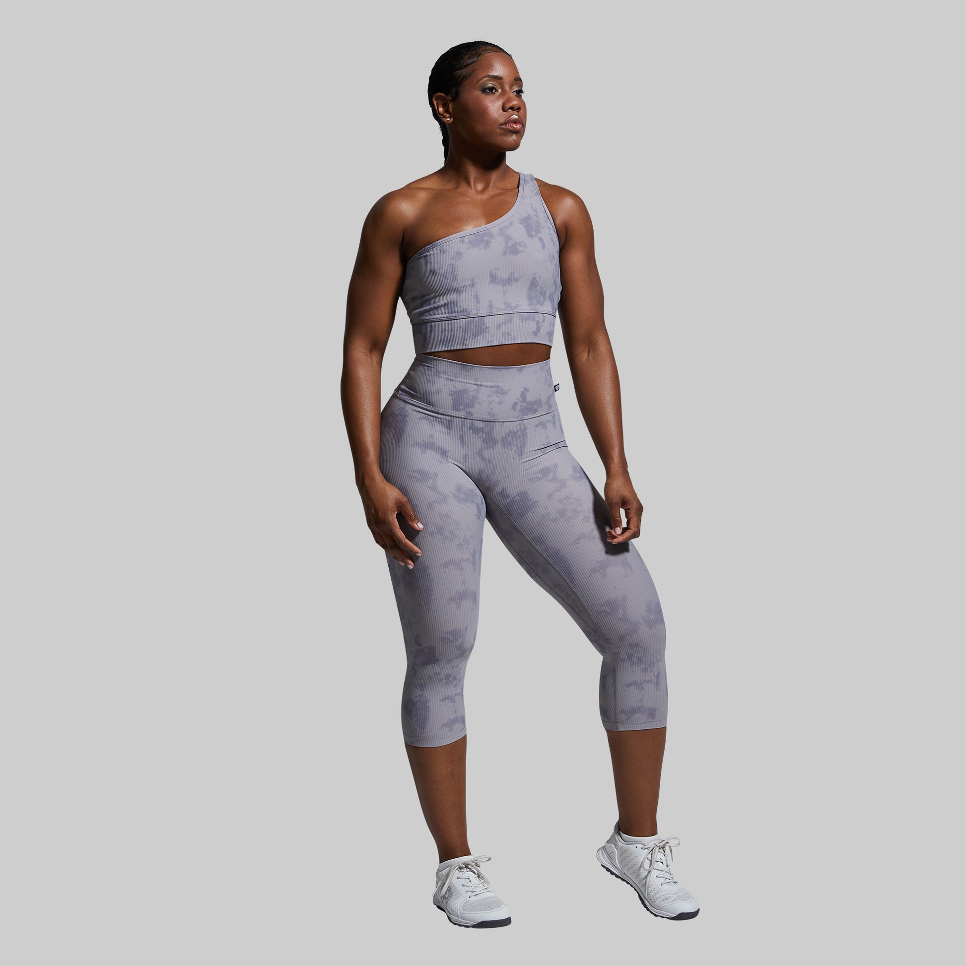 Woman wearing a gray athletic outfit on a plain background