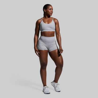 Woman wearing a gray athletic outfit on a plain background