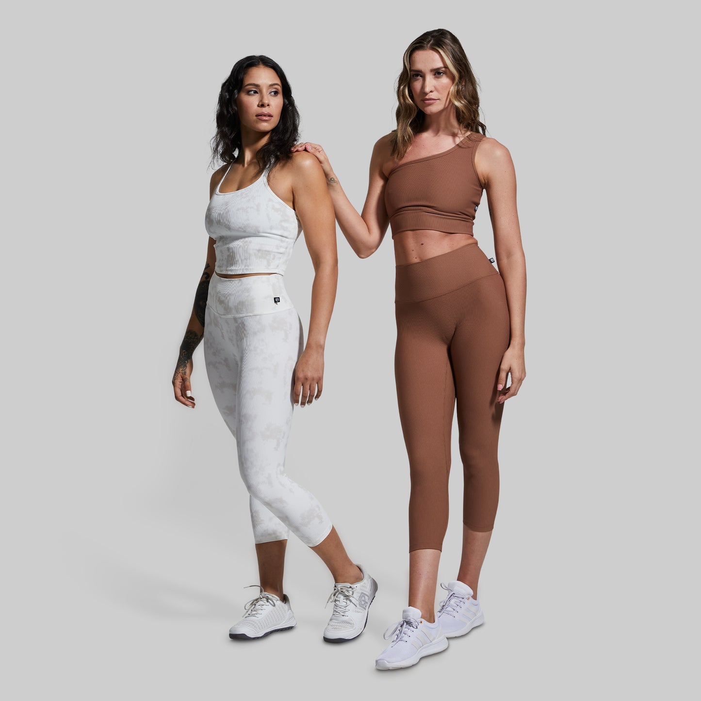 Two women wearing matching athletic outfits on a plain background