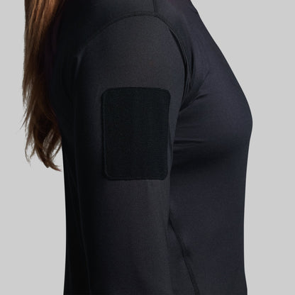 Person wearing a black long-sleeve shirt with a velcro patch on a gray background