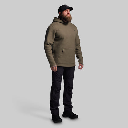 Man wearing a green hoodie and black pants on a gray background