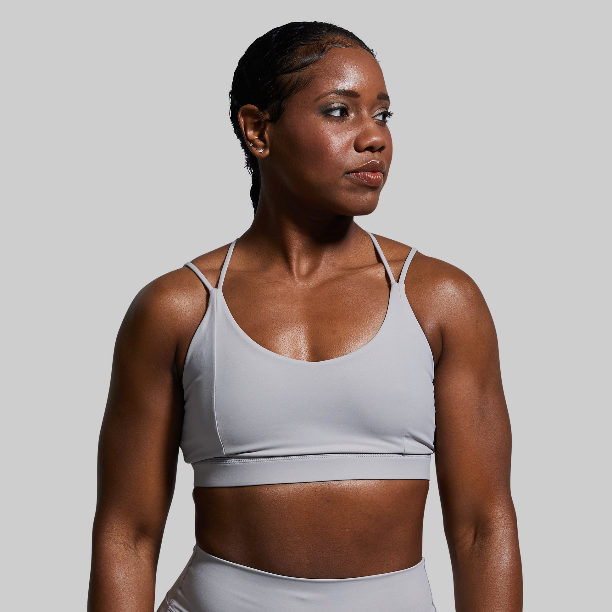 Woman wearing a gray sports bra and leggings against a plain background