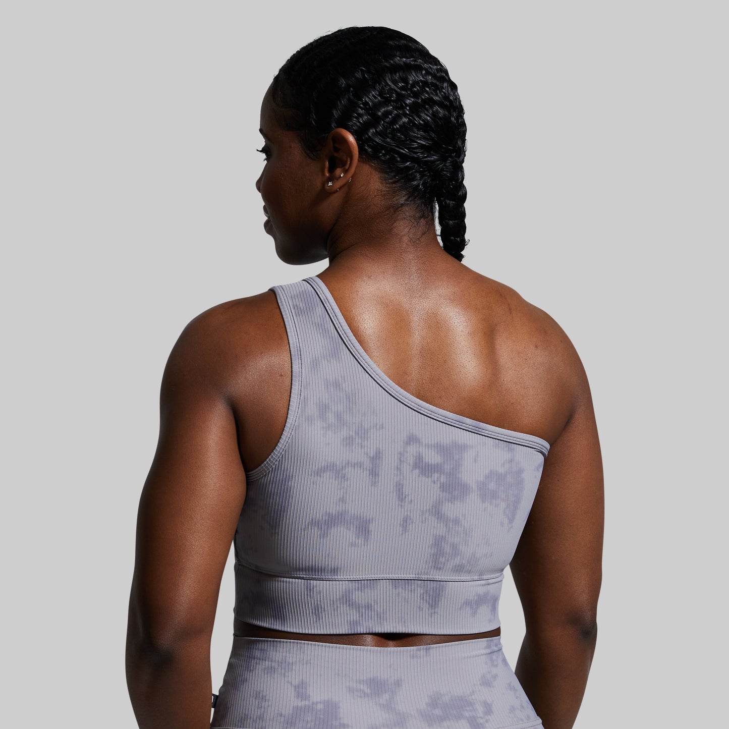 Person wearing a gray sports bra with a subtle pattern on a plain background