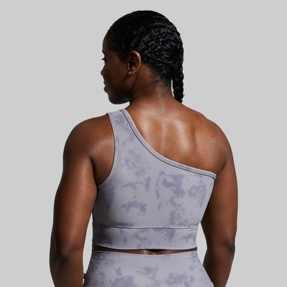 Person wearing a gray sports bra with a subtle pattern on a plain background