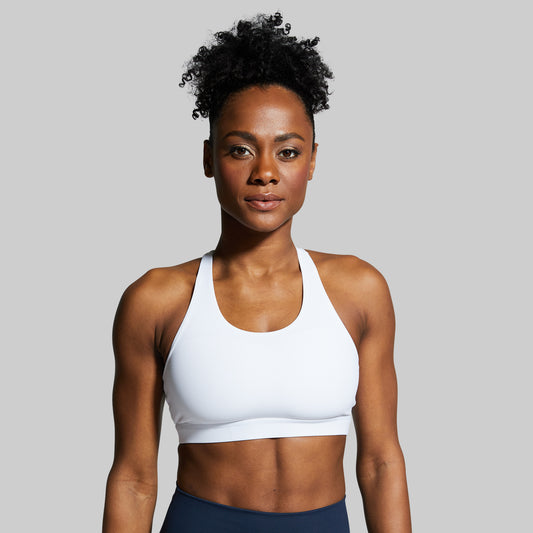 Woman wearing a white sports bra against a gray background