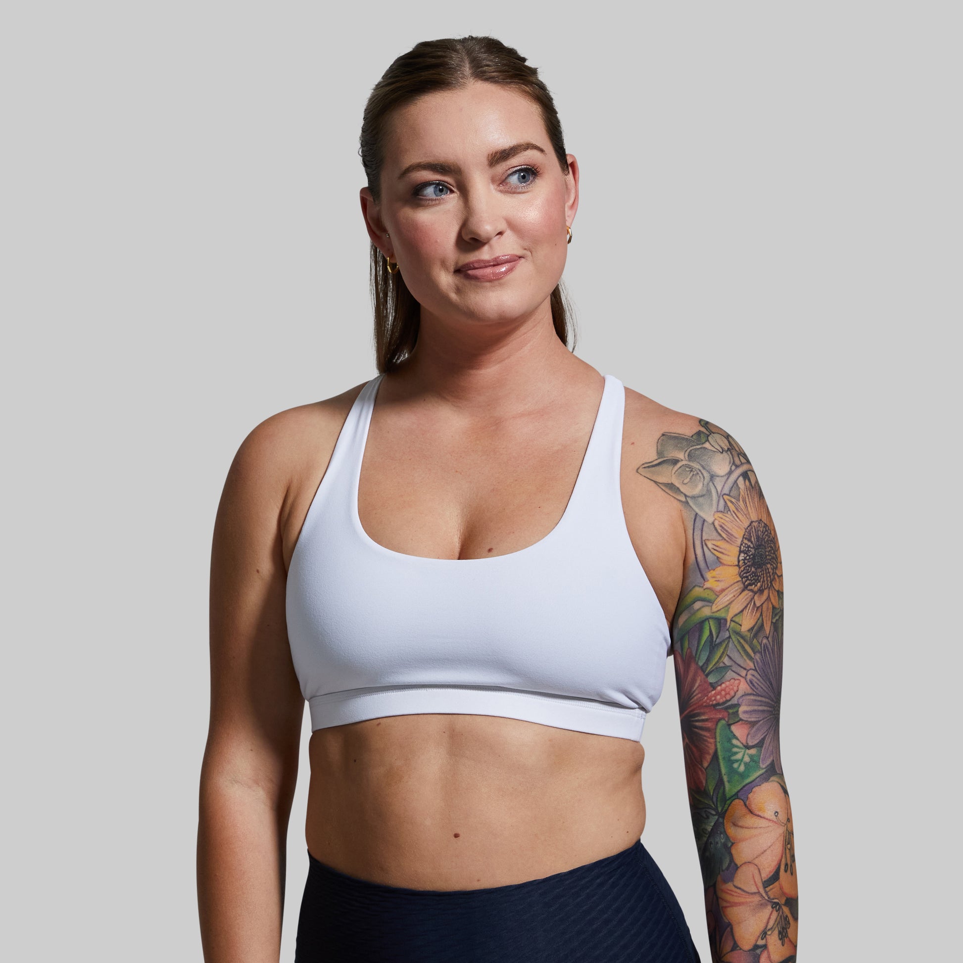 Woman wearing a white sports bra and black leggings against a plain background