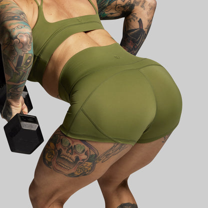 Person wearing green athletic wear holding a dumbbell on a gray background