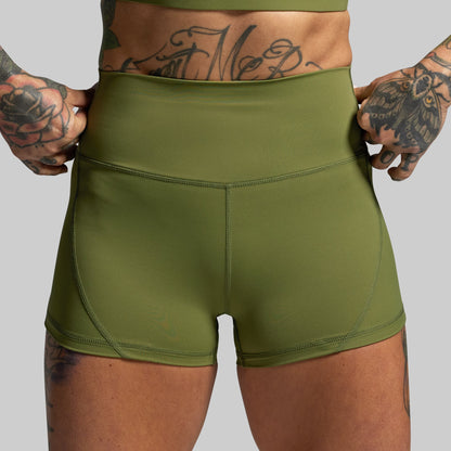 Person wearing green athletic shorts with a gray background
