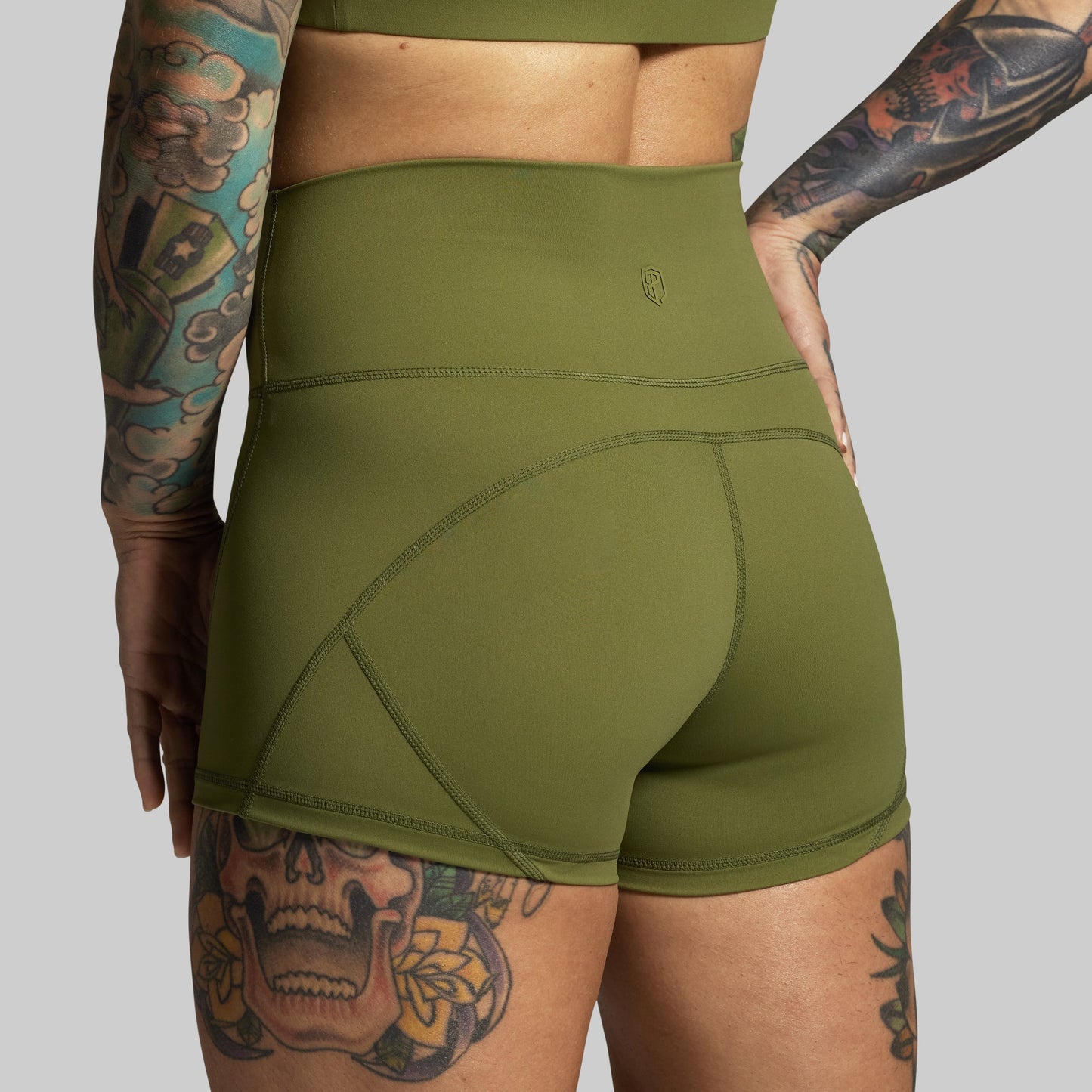 Green athletic shorts worn by a person with tattoos on a plain background