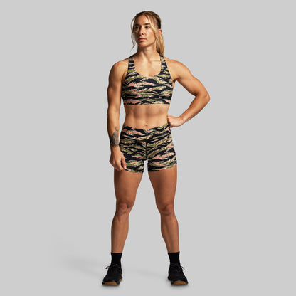 Woman wearing a camouflage sports bra and shorts set on a gray background