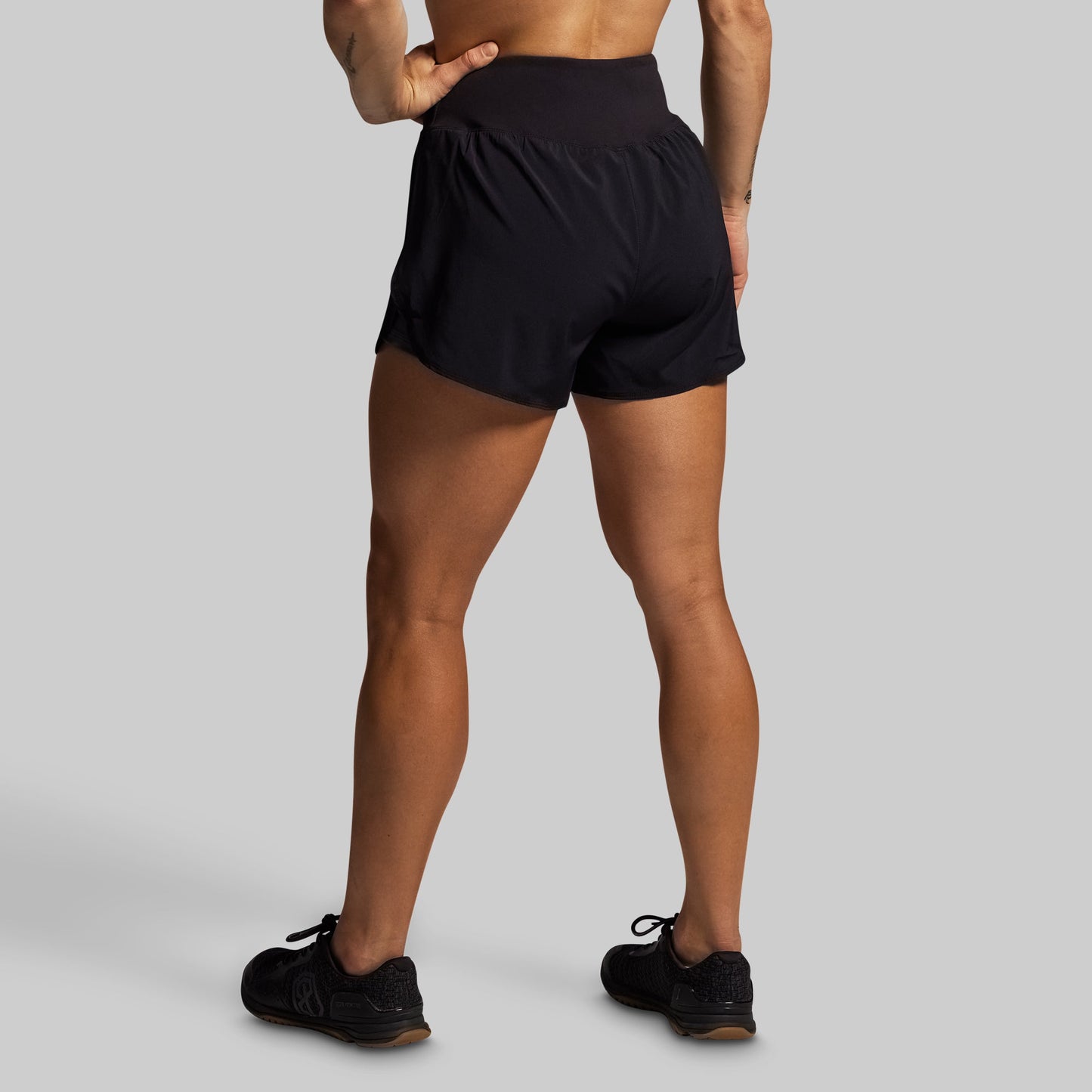 Person wearing black athletic shorts on a gray background