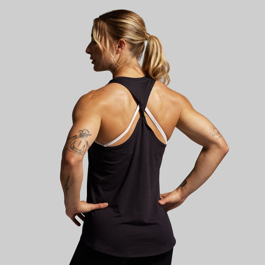 Woman wearing a black tank top with thin straps on a gray background