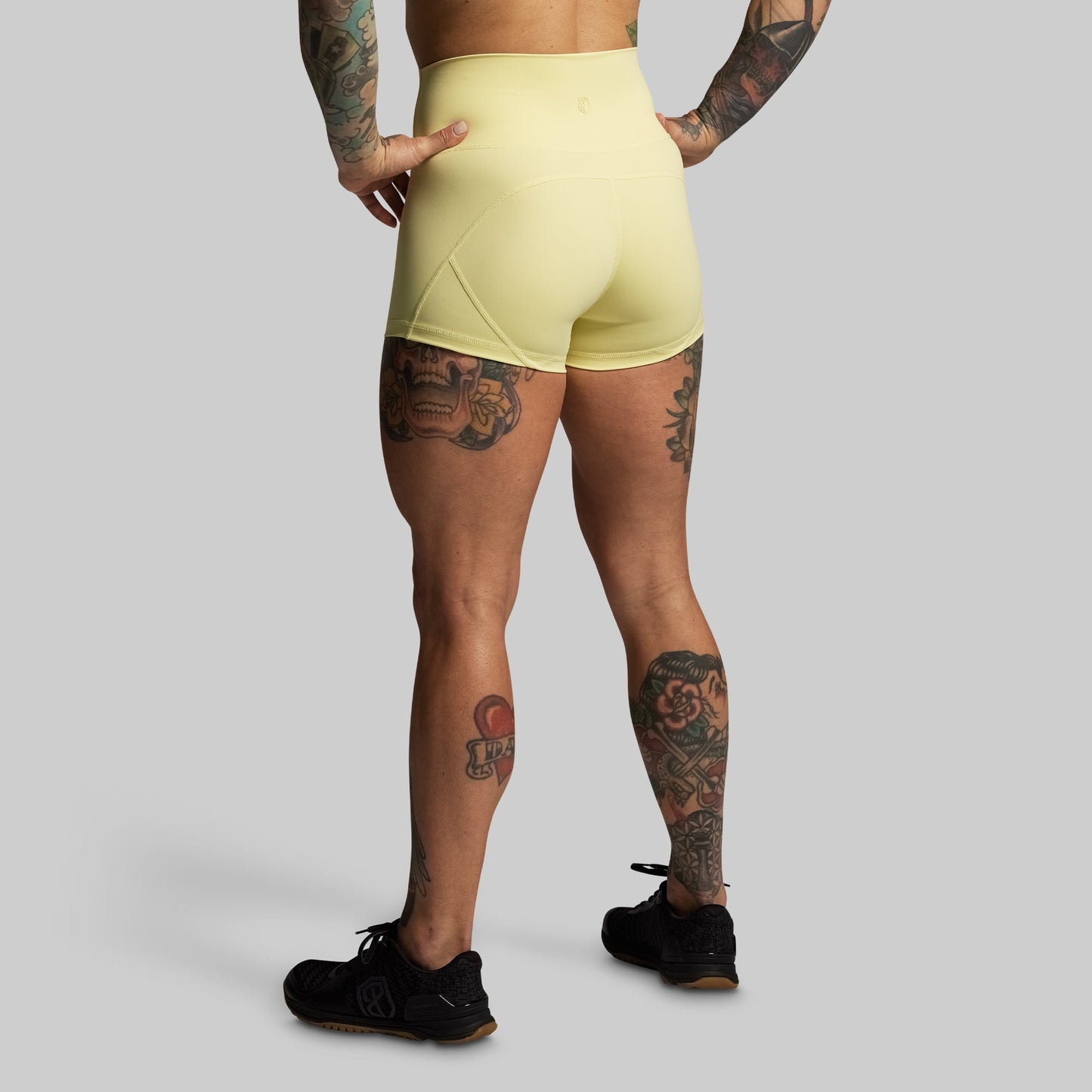 Person wearing light yellow athletic shorts on a gray background