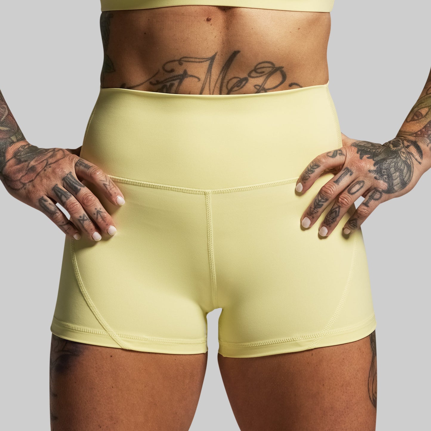 Person wearing light yellow athletic shorts with a plain background