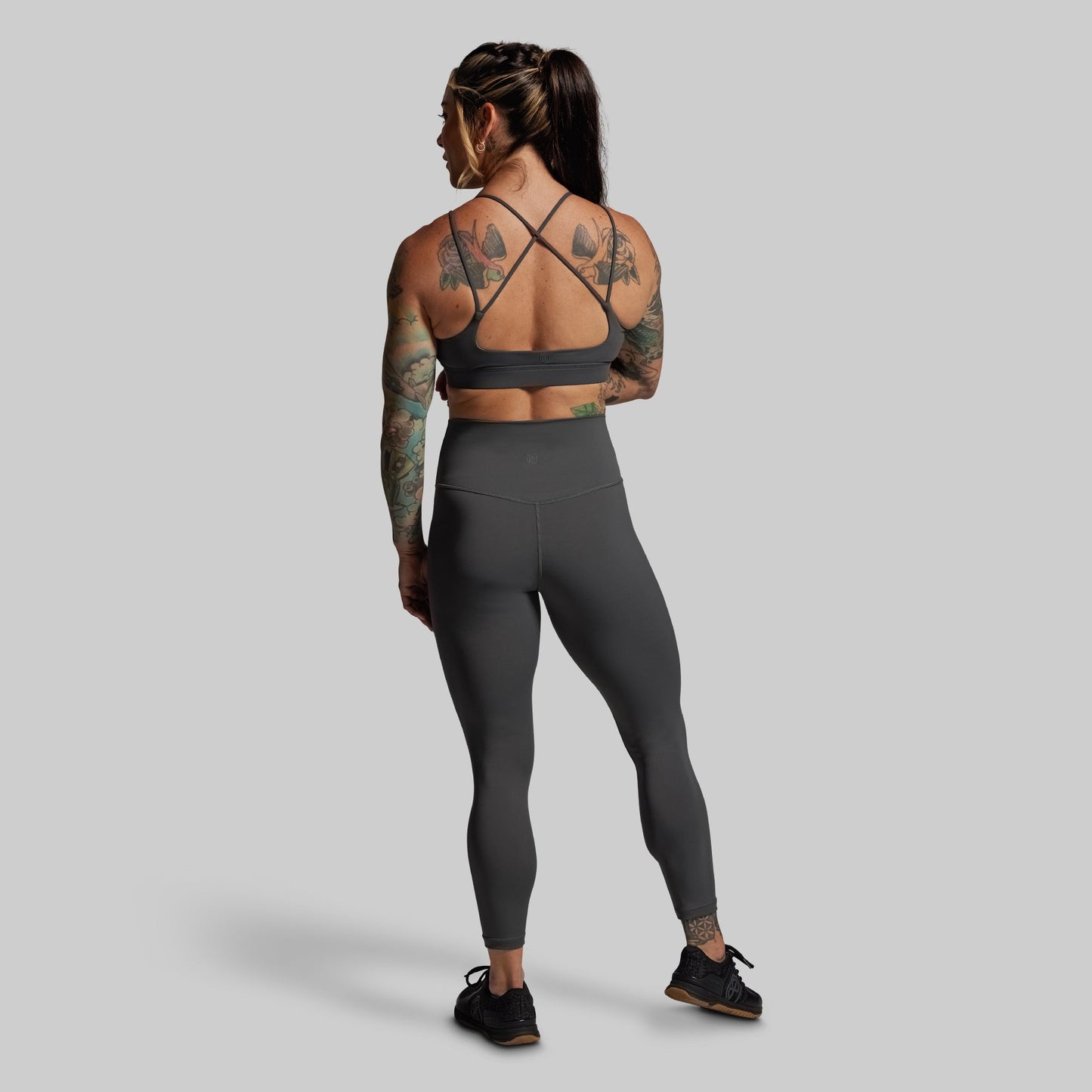 Person wearing a gray sports bra and leggings set on a plain background