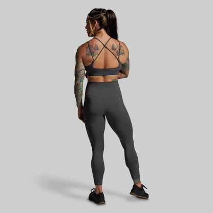 Person wearing a gray sports bra and leggings set on a plain background