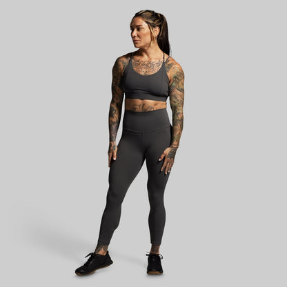 Woman wearing a gray athletic outfit on a plain background