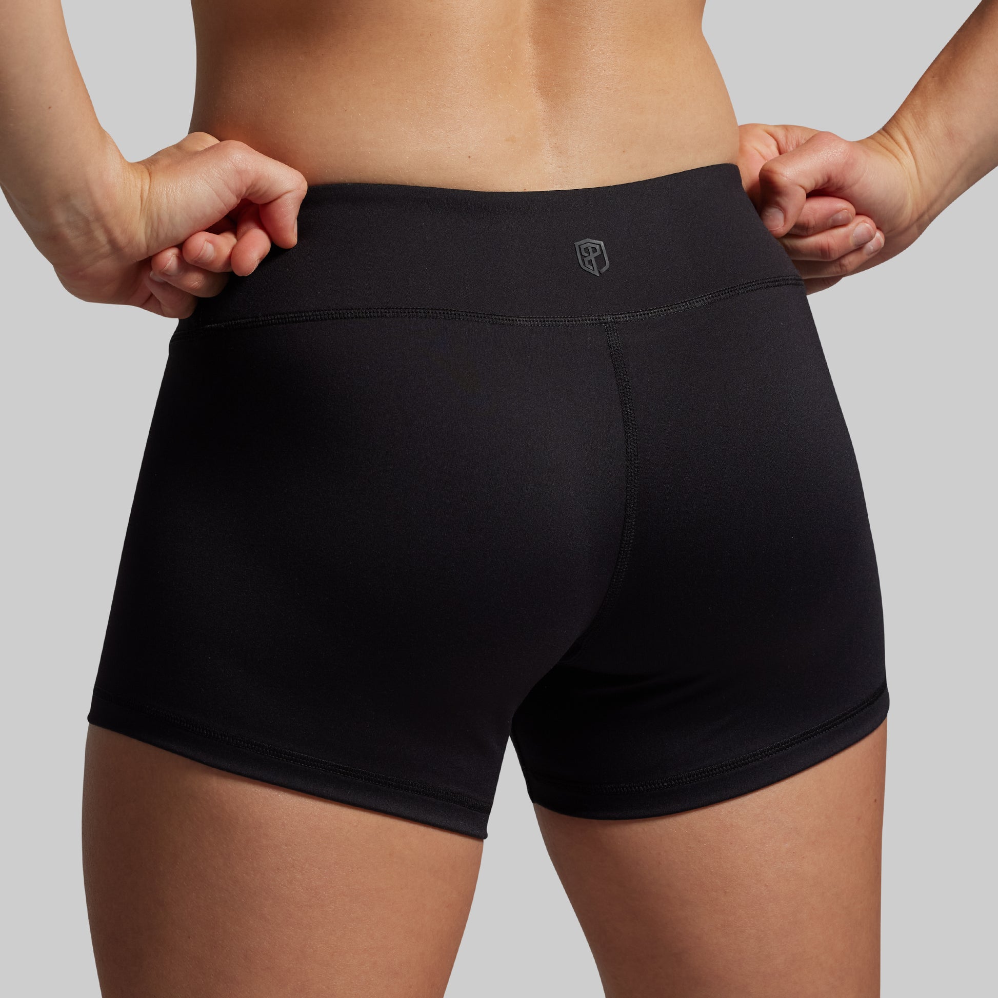 Black athletic shorts worn by a person on a gray background