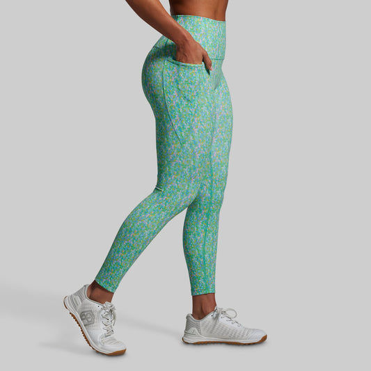 Person wearing green floral leggings on a gray background