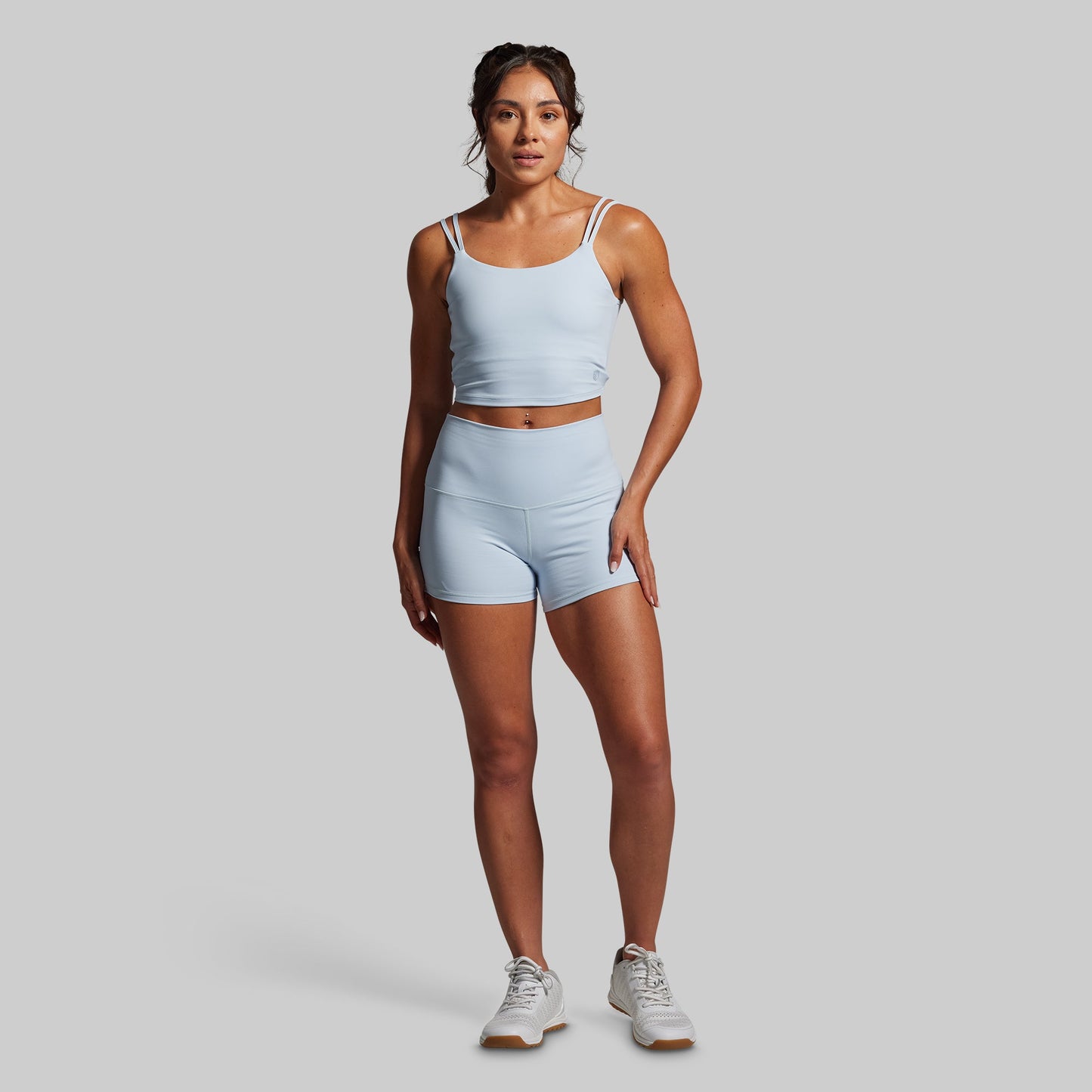 Woman wearing a light blue athletic outfit on a gray background