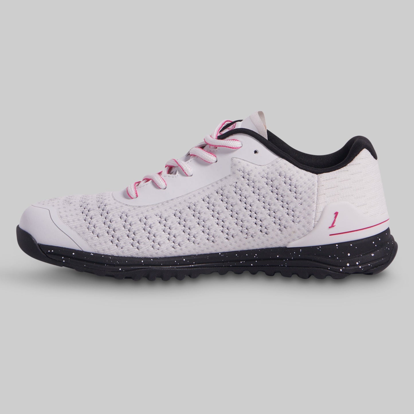 White athletic shoe with black sole and pink laces on a gray background