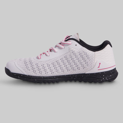 White athletic shoe with black sole and pink laces on a gray background