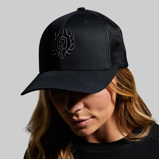 Person wearing a black cap with a logo on a gray background