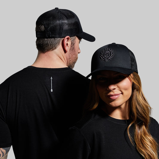 Man and woman wearing black caps with a logo on a gray background