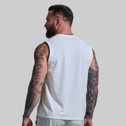 Man wearing a white sleeveless shirt with tattoos on arms against a plain background