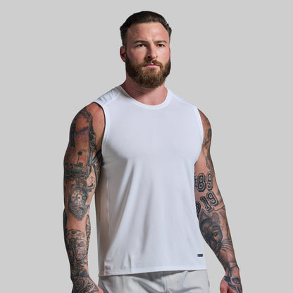 Man wearing a white tank top with tattoos on arms against a plain background