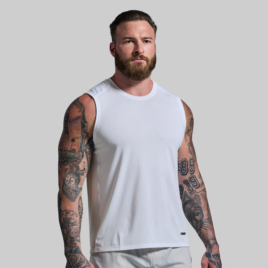 Man wearing a white tank top with tattoos on arms against a plain background