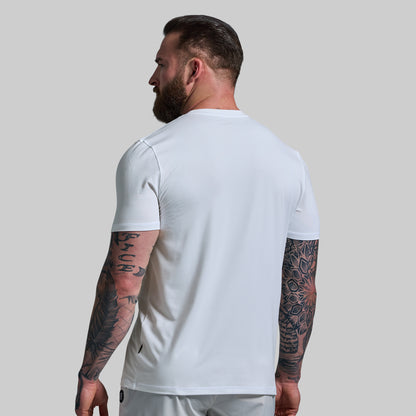 Man wearing a white t-shirt with tattoos on arms against a plain background