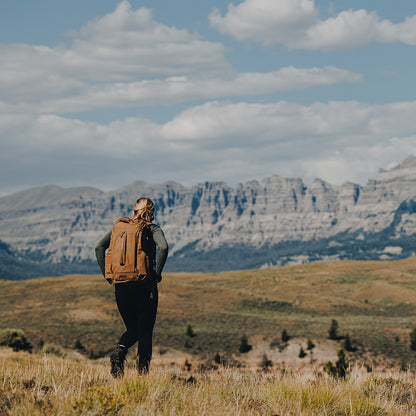 Woman in valley with mountain in the background wearing outdoor gear.