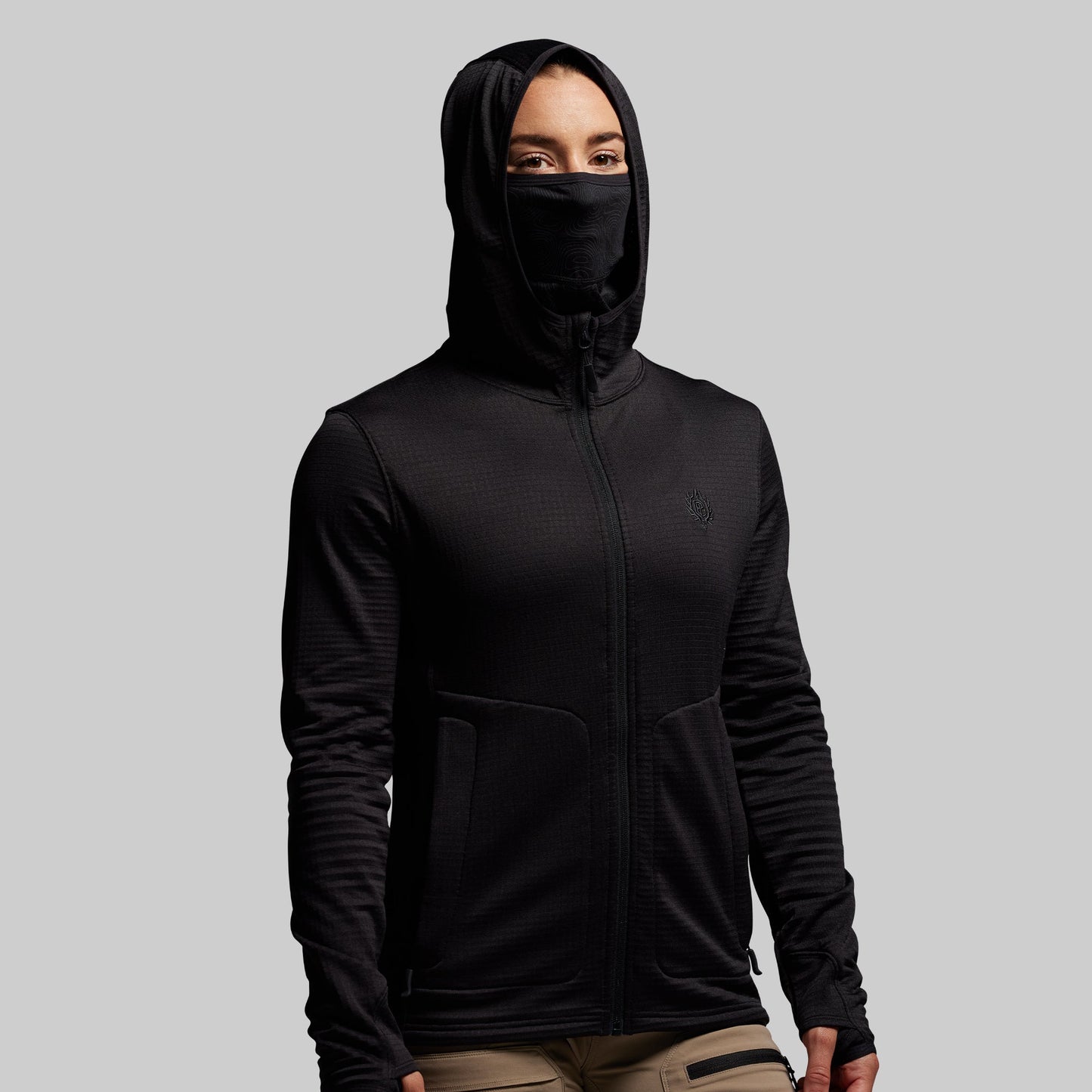 Person wearing a black hoodie with a built in face mask on a gray background
