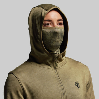 Person wearing a green hoodie with a built in face mask on a gray background