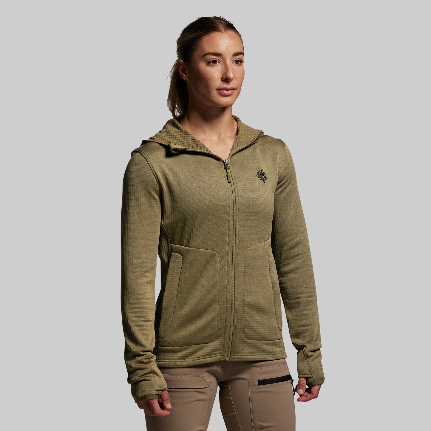 Woman wearing a green hoodie with a logo on a gray background