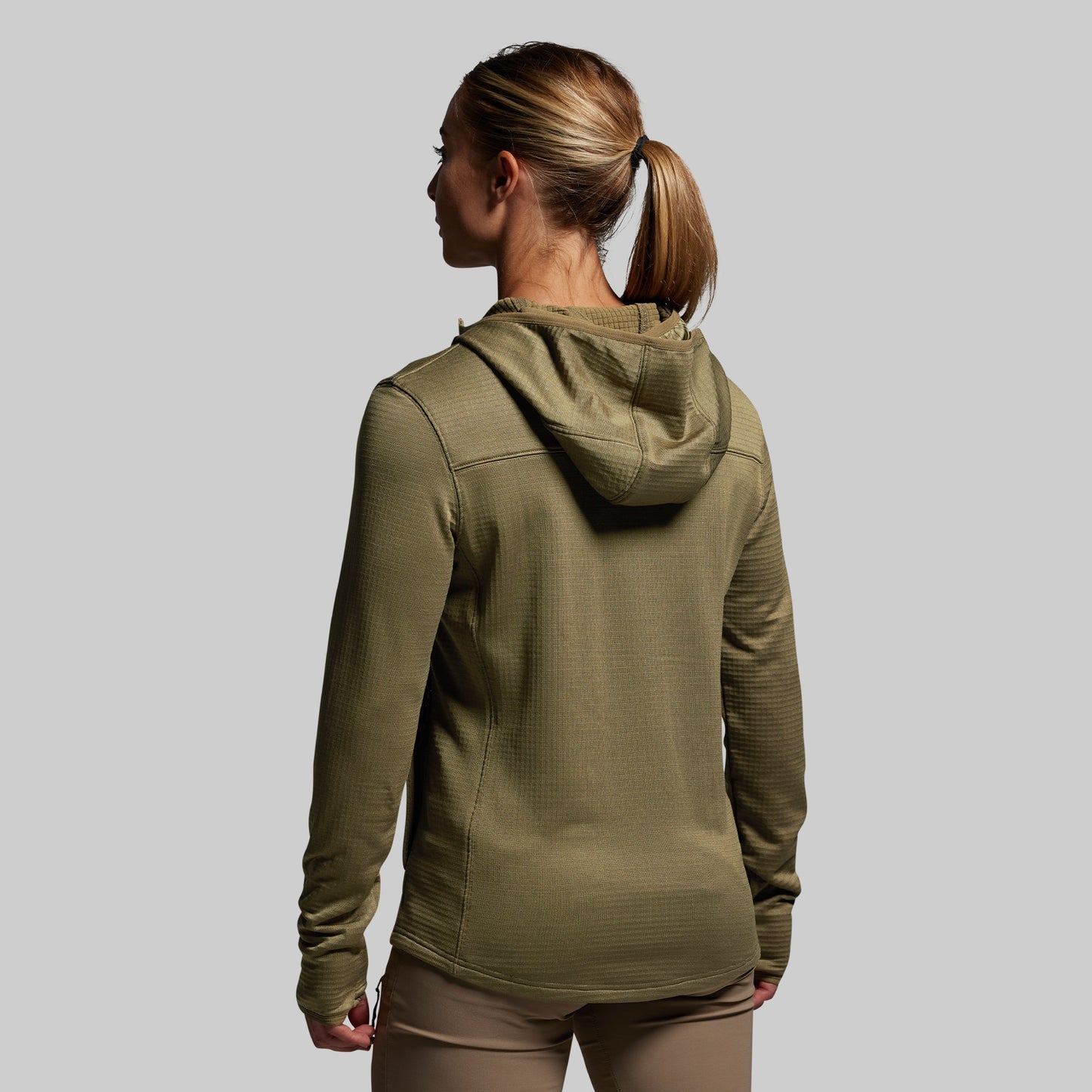 Person wearing a green hoodie on a plain background