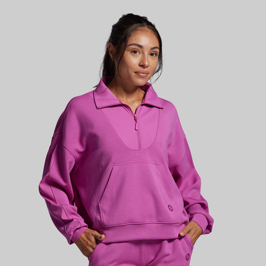 Person wearing a pink tracksuit against a gray background