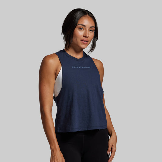 Woman wearing a navy blue sleeveless top with a brand logo on a gray background