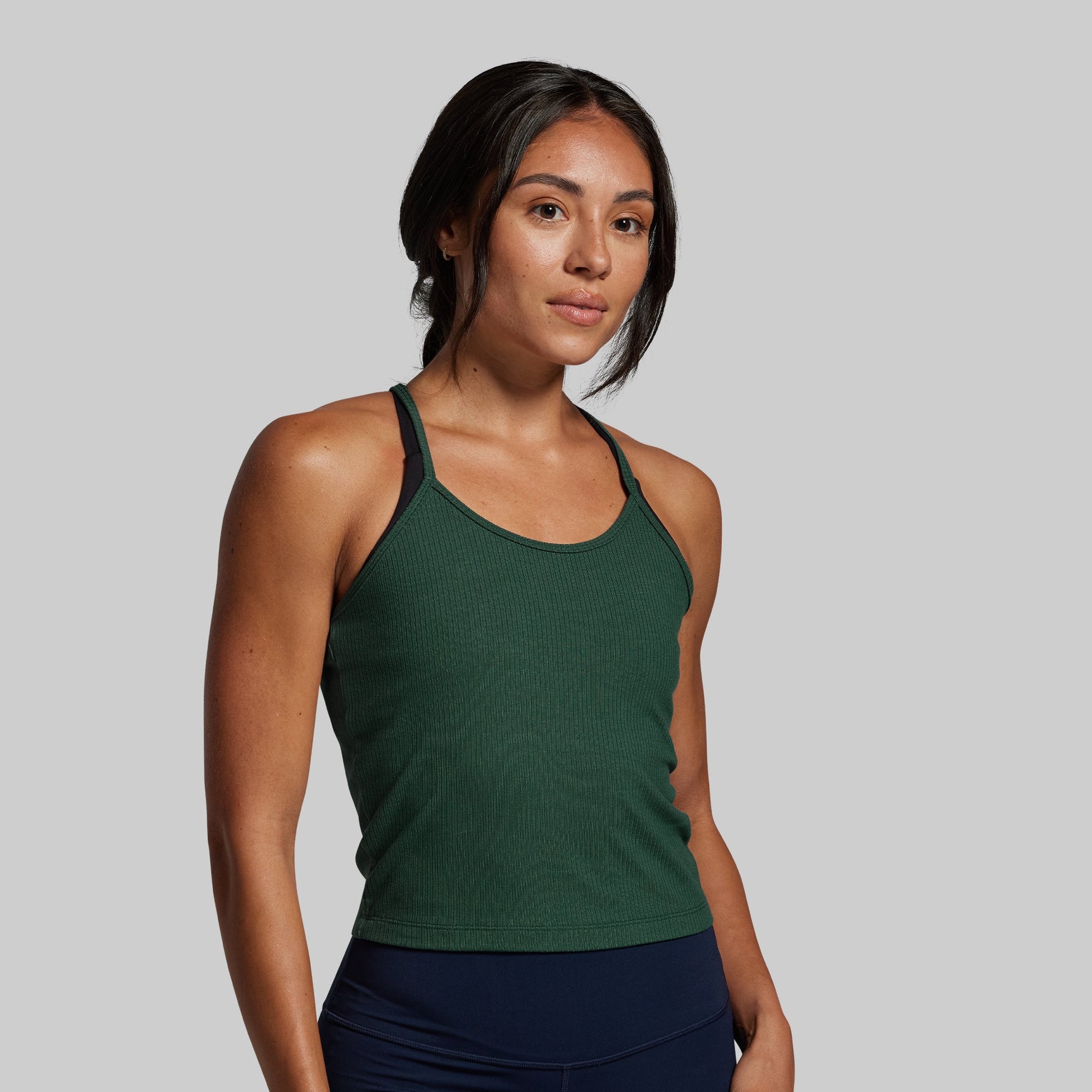 Woman wearing a green tank top against a gray background