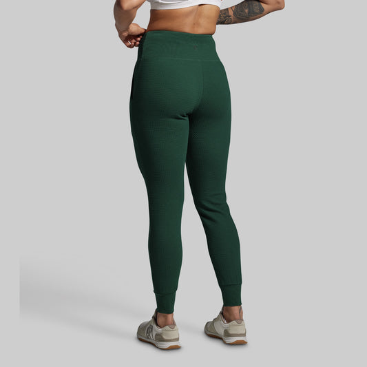 Person wearing green joggers on a gray background