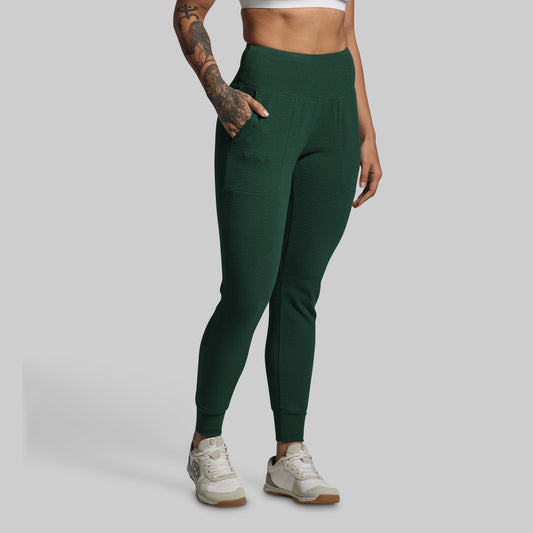 Person wearing green jogger pants on a gray background
