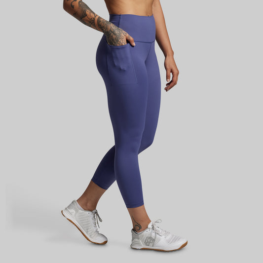 Person wearing blue leggings and white sneakers on a gray background