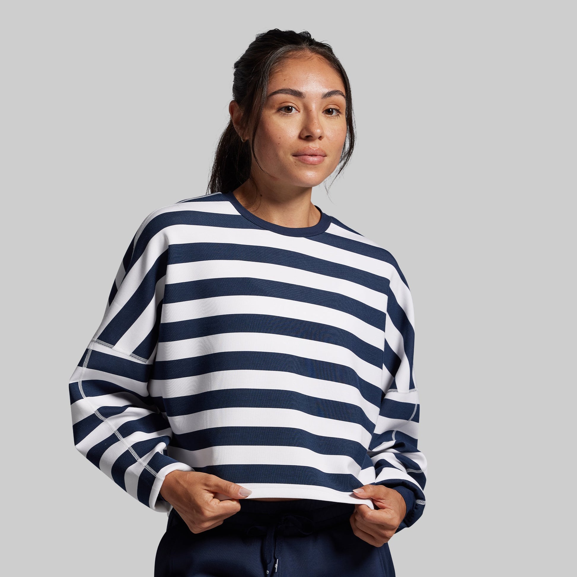 Woman wearing a navy and white striped sweater against a gray background