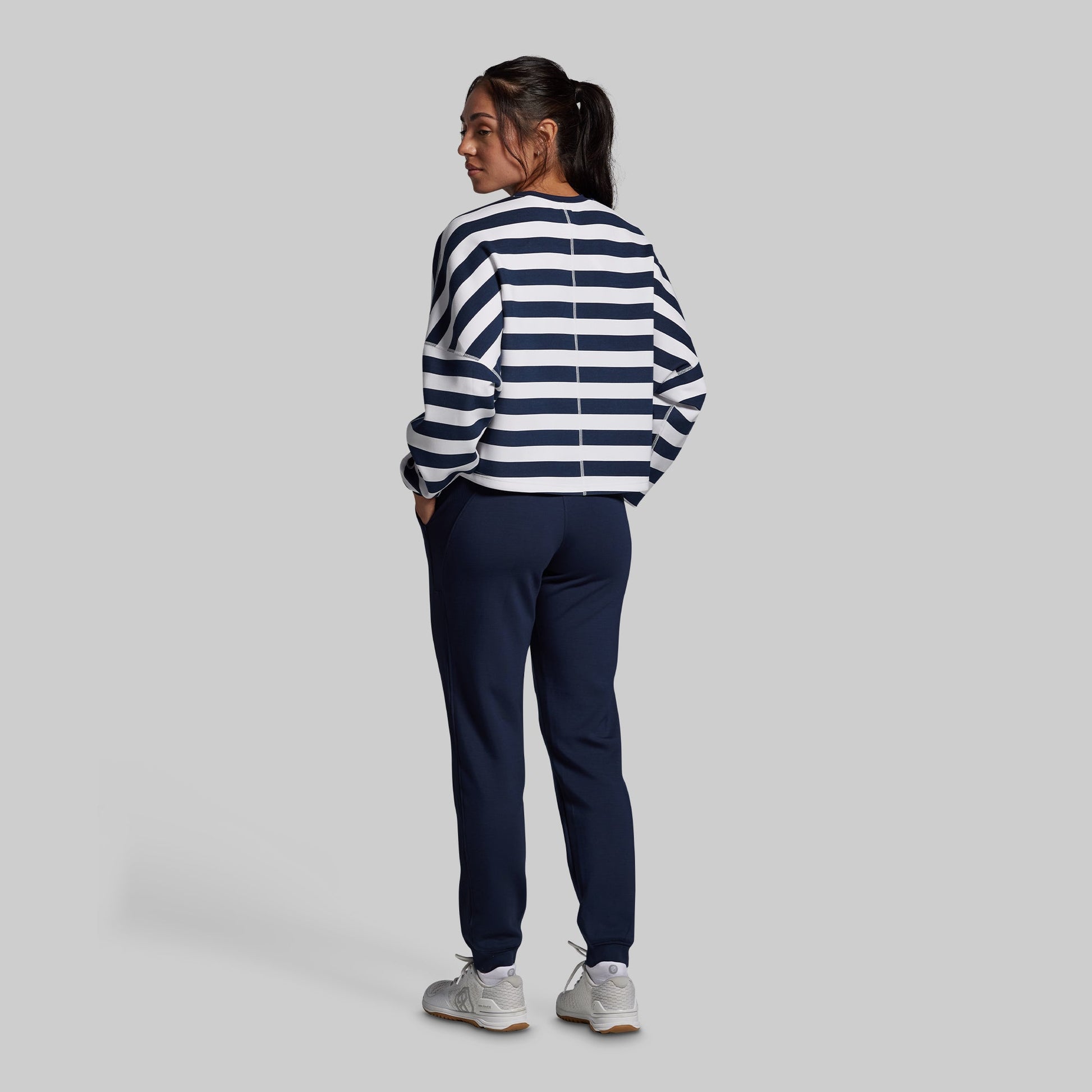 Person wearing a striped sweater and navy pants on a plain background