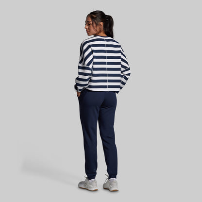 Person wearing a striped sweater and navy pants on a plain background