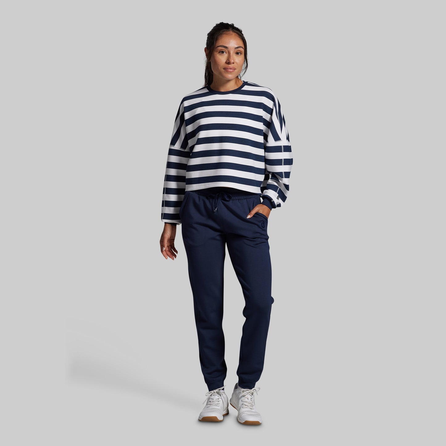 Person wearing a navy and white striped sweater with navy pants on a gray background