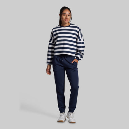 Person wearing a navy and white striped sweater with navy pants on a gray background