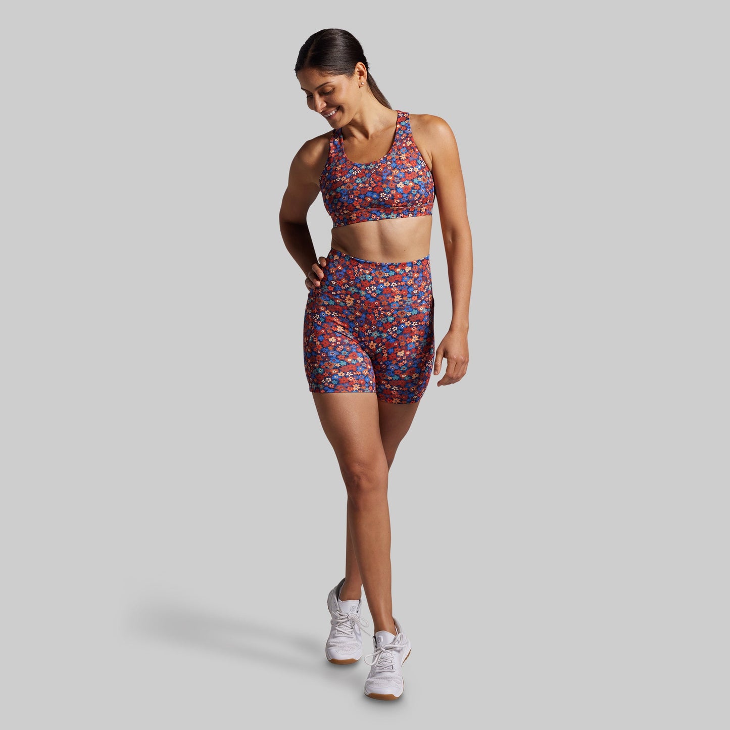 Woman wearing a colorful sports bra and shorts set on a gray background